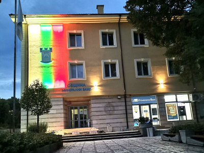 Фасадата на община Минерални бани свети в бяло, зелено, червено